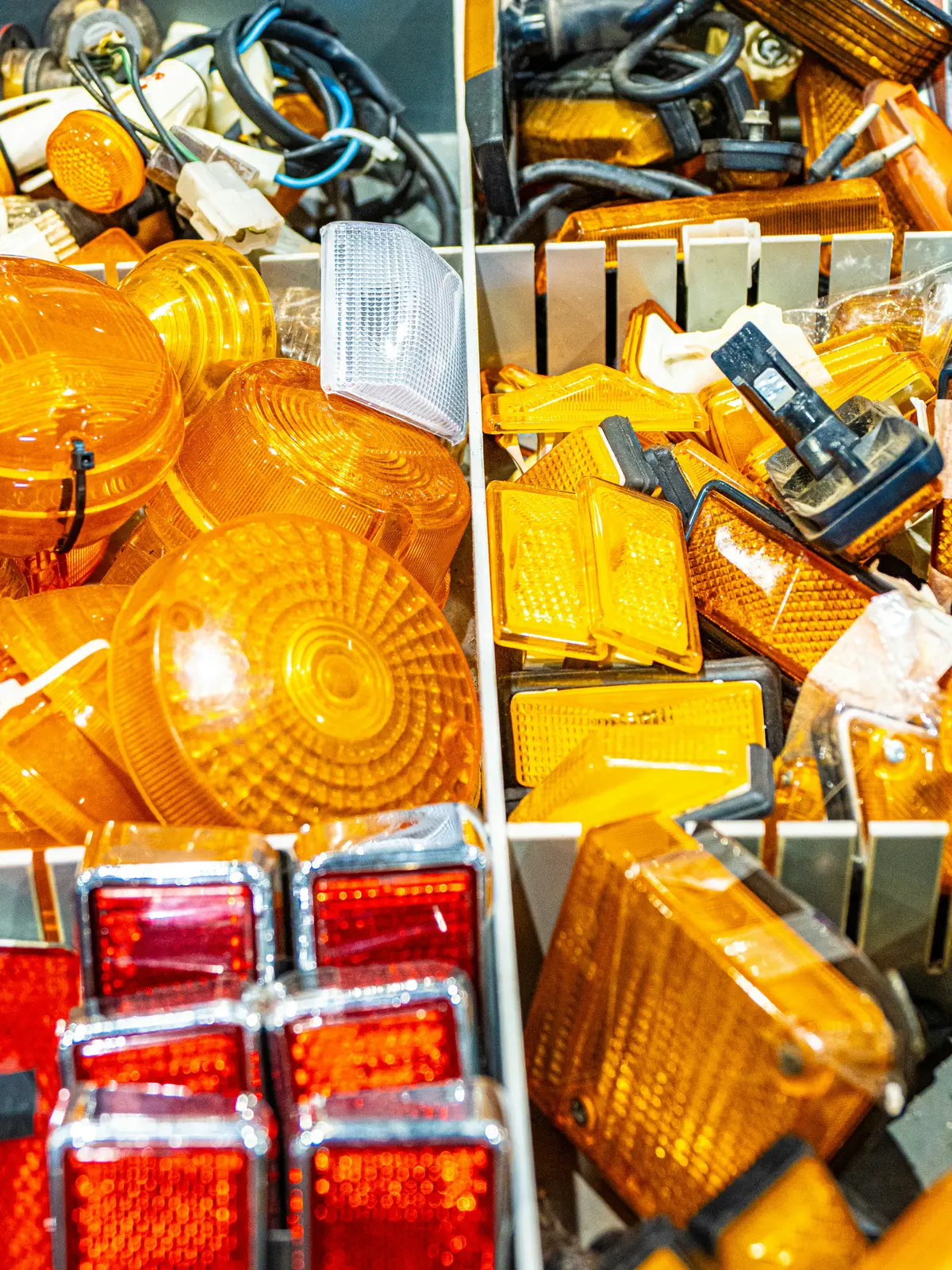 Assortimento di fanaleria e ricambi per auto suddivisi in contenitori